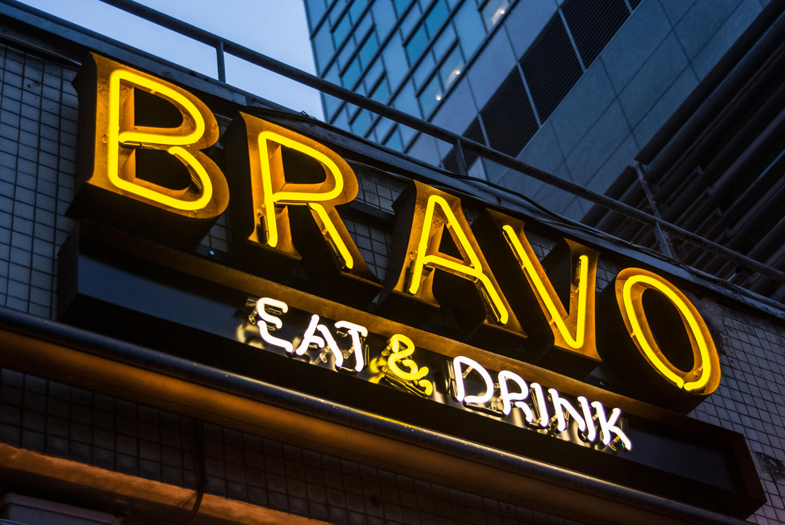 neon-bravo-eat-drink-neon-nad-wejsciem-do-restauracji-neon-na-kaflach-neon-na-scianie-z-kafli-neon-podswietlany-neon-wewnatrz-blachy-nierdzewnej-neon-na-zewnatrz-zolty-neon-warszawa-centralna